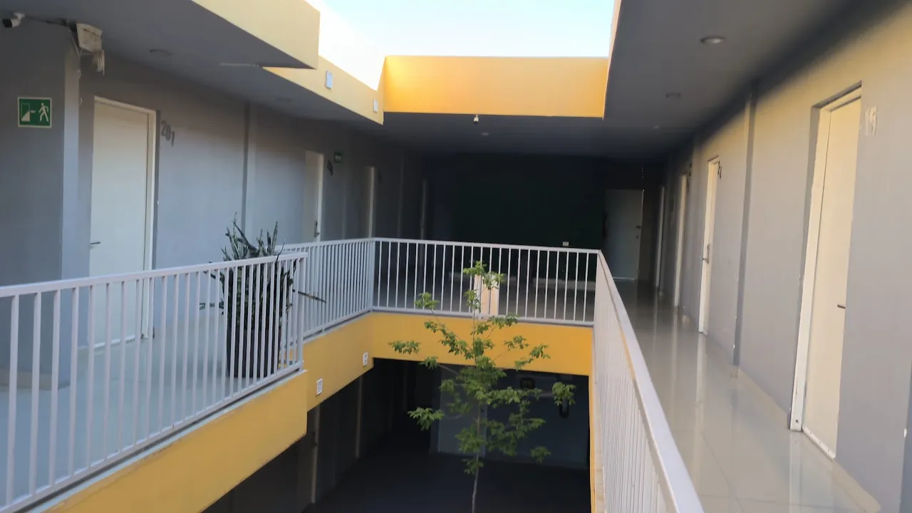 Pasillo con barandal blanco, puertas de habitaciones y tragaluz amarillo