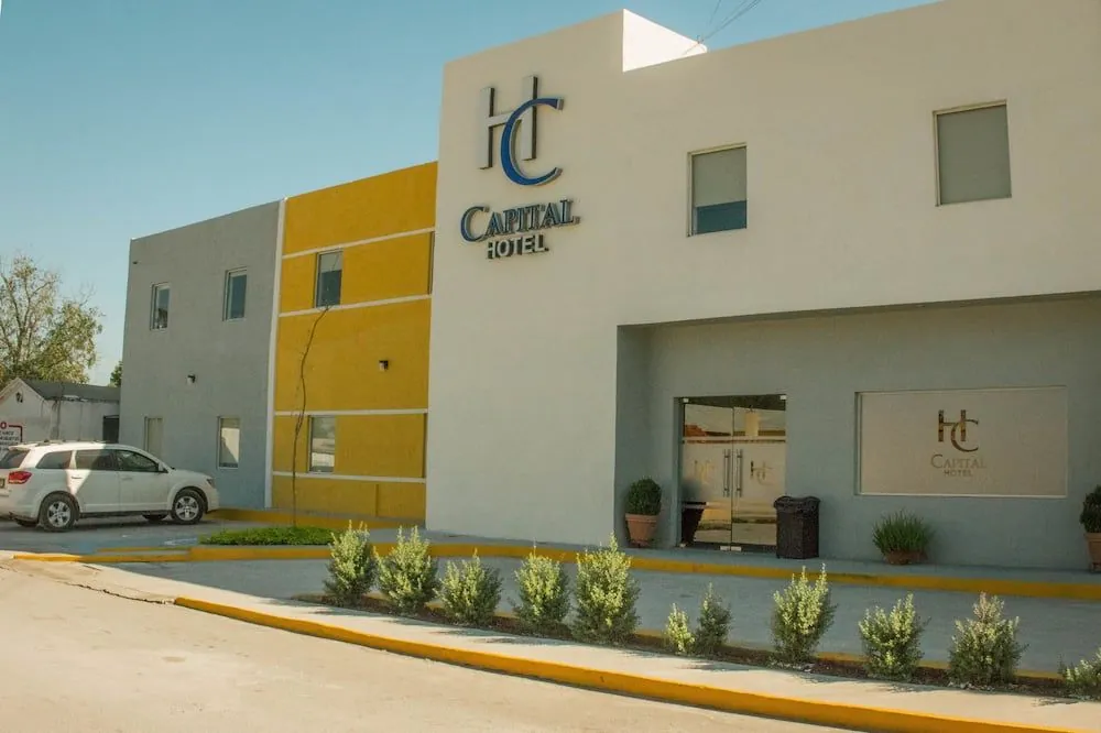 Capital Hotel Monclova visto desde la calle: fachada blanca con el logo, muro amarillo y jardineras