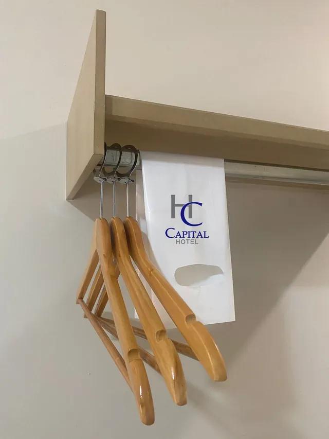 Ganchos de madera y bolsa de lavandería con el logo de Capital Hotel en el clóset